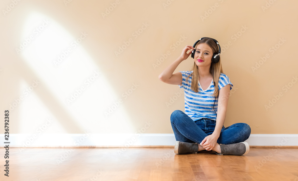 戴着耳机的年轻女子靠着一堵大内墙