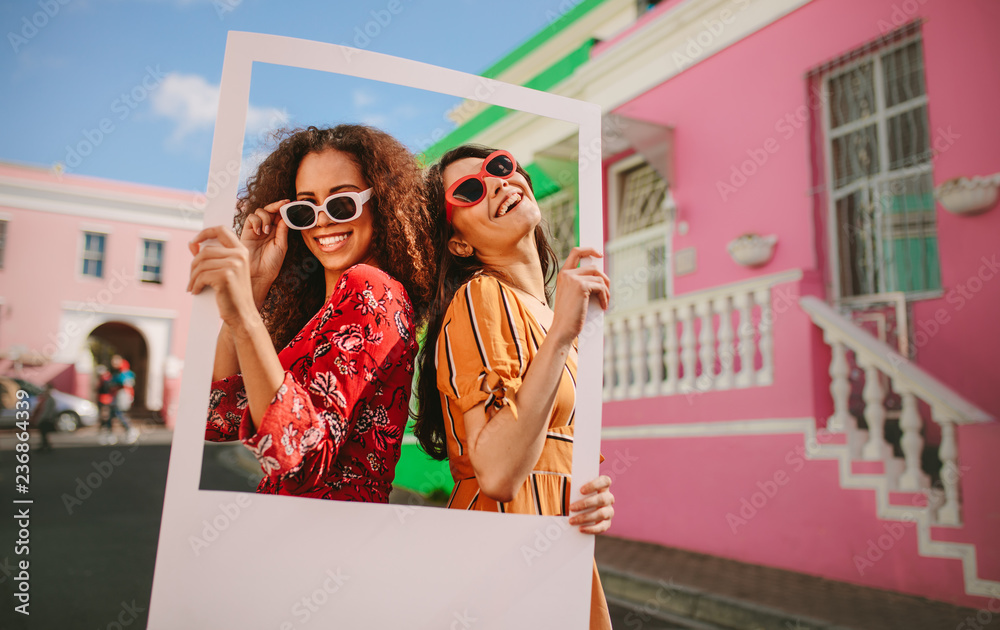 Beautiful friends enjoying outdoors with a picture frame