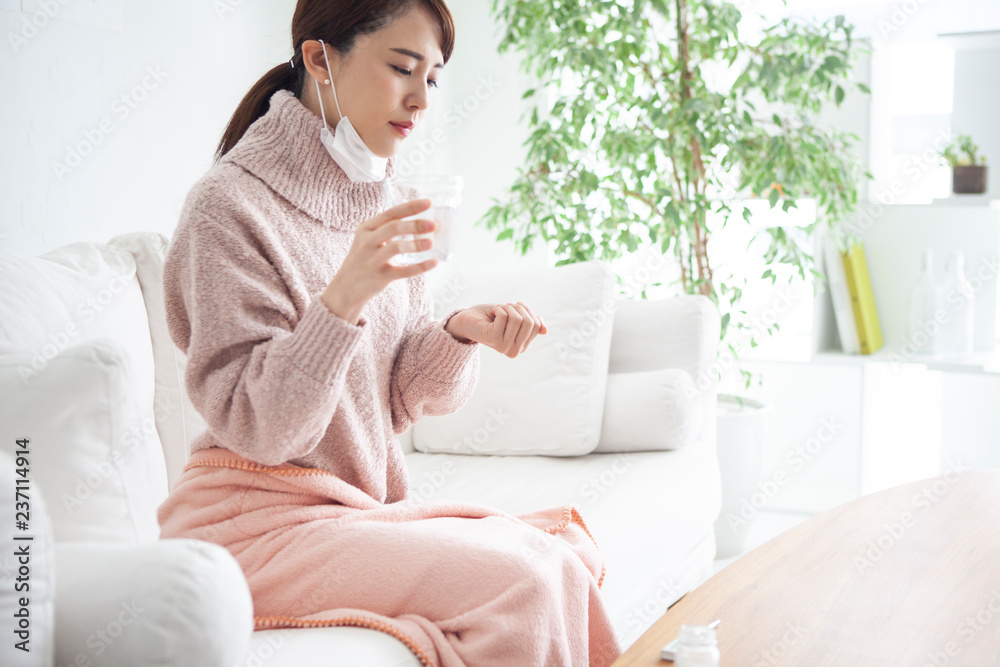 風邪をひいてしまい自宅で薬を飲む女性