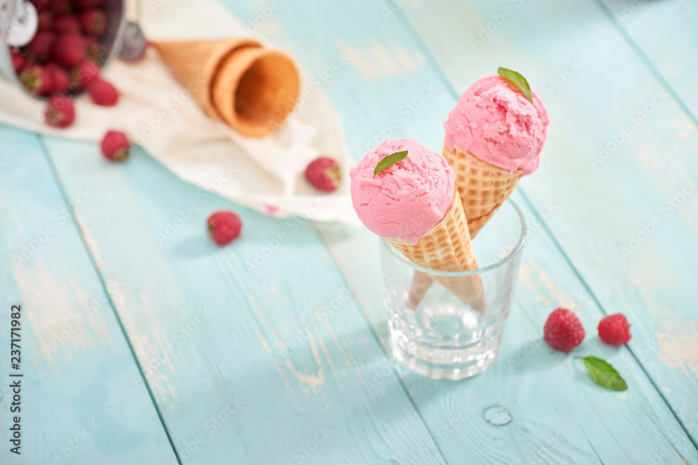 Homemade raspberry ice cream in waffle cones on rustic wooden background, selective focus. Summer ti