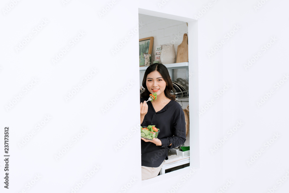 Healthy diet. Beautiful smiling woman eating fresh organic salad in modern kitchen. Healthy eating, 