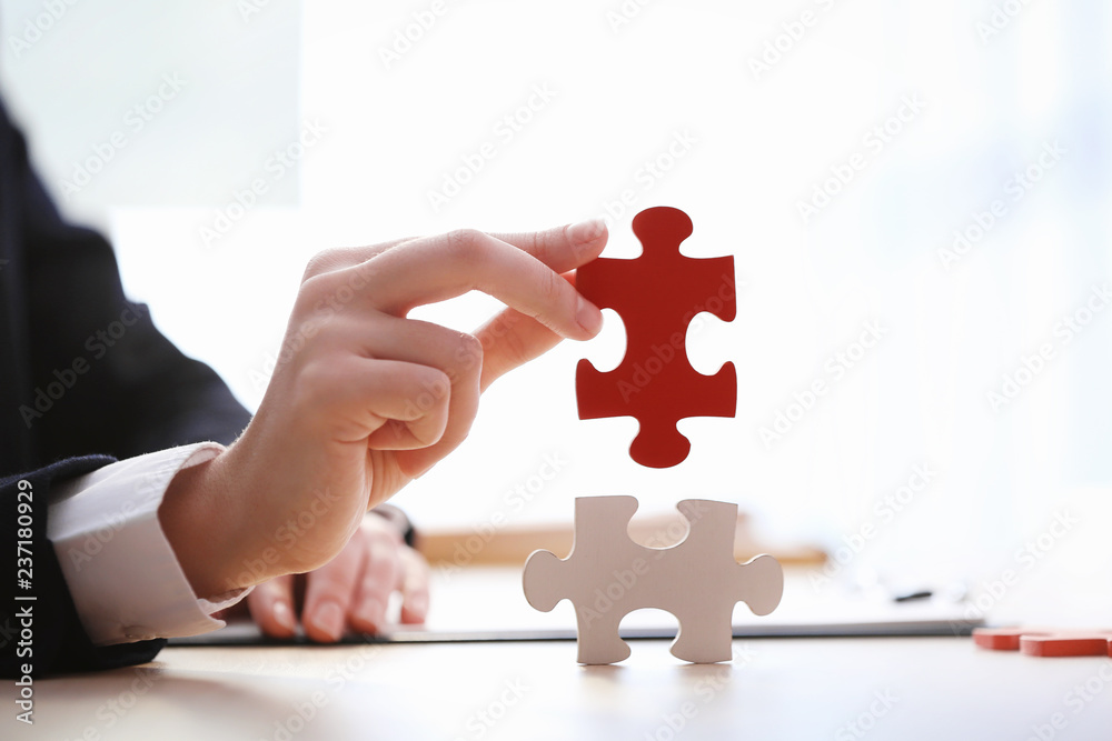 Woman with pieces of color puzzle at table, closeup