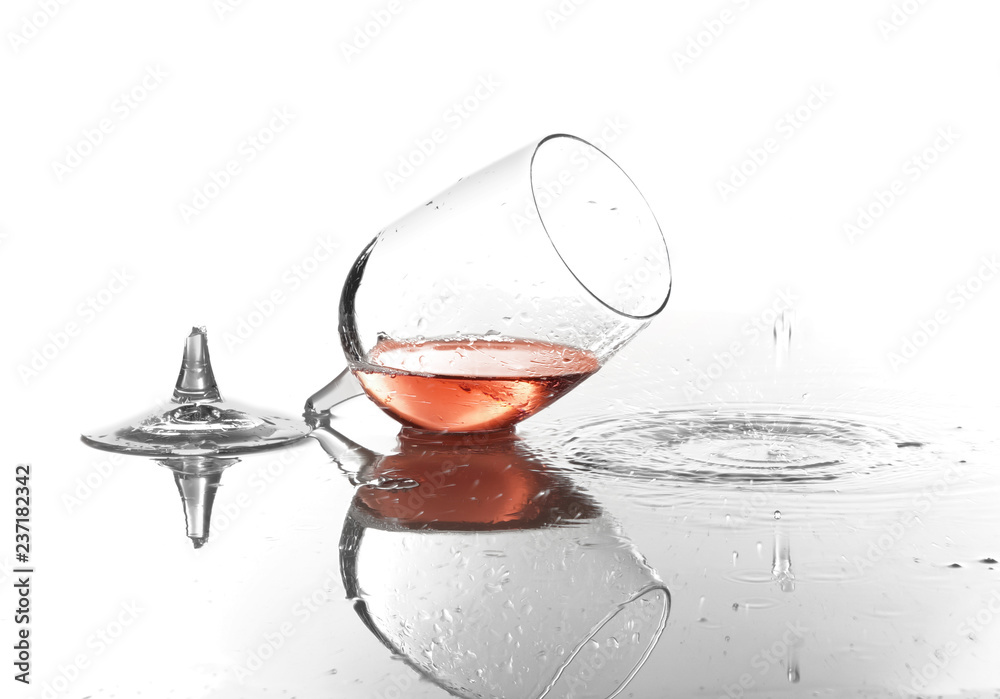 Broken glass with spilled red wine on white background