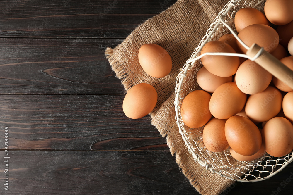 Basket with raw chicken eggs on dark wooden table