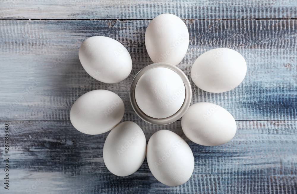 Holder with raw chicken eggs on wooden table