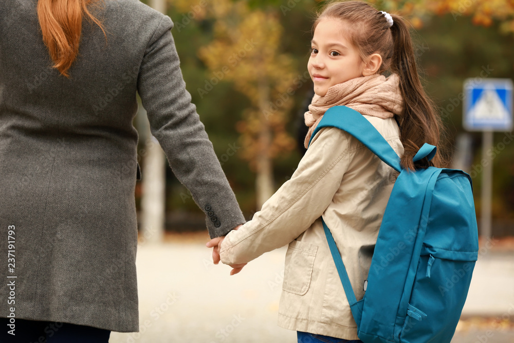 Cute girl going to school with her mother outdoors