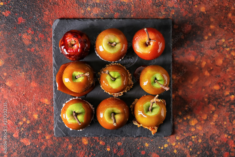 Delicious caramel apples with tree branches on slate plate