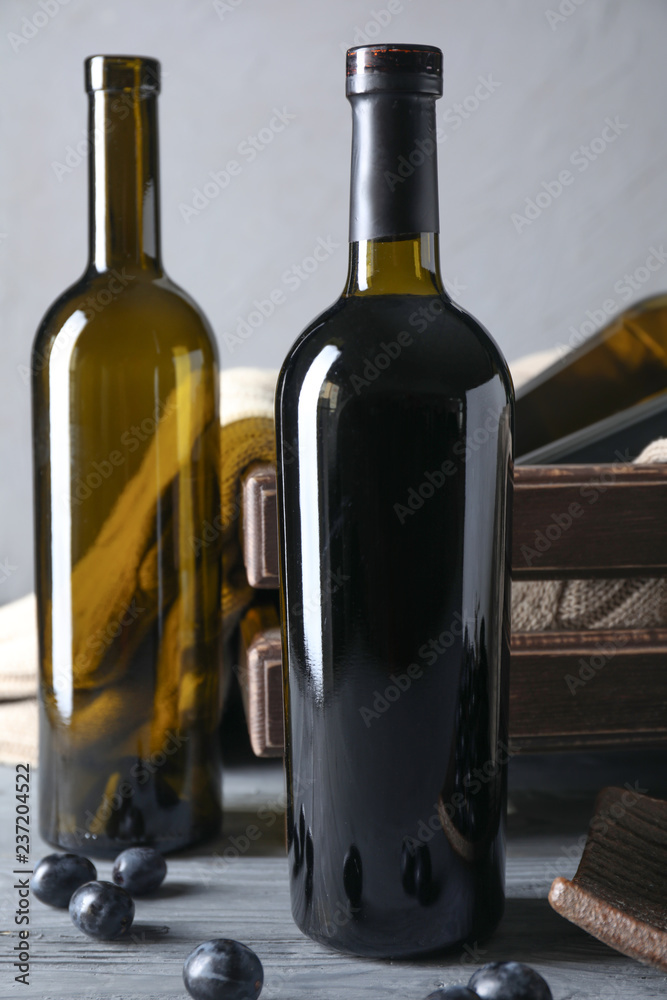 Empty and full bottles of wine  with grapes on wooden table