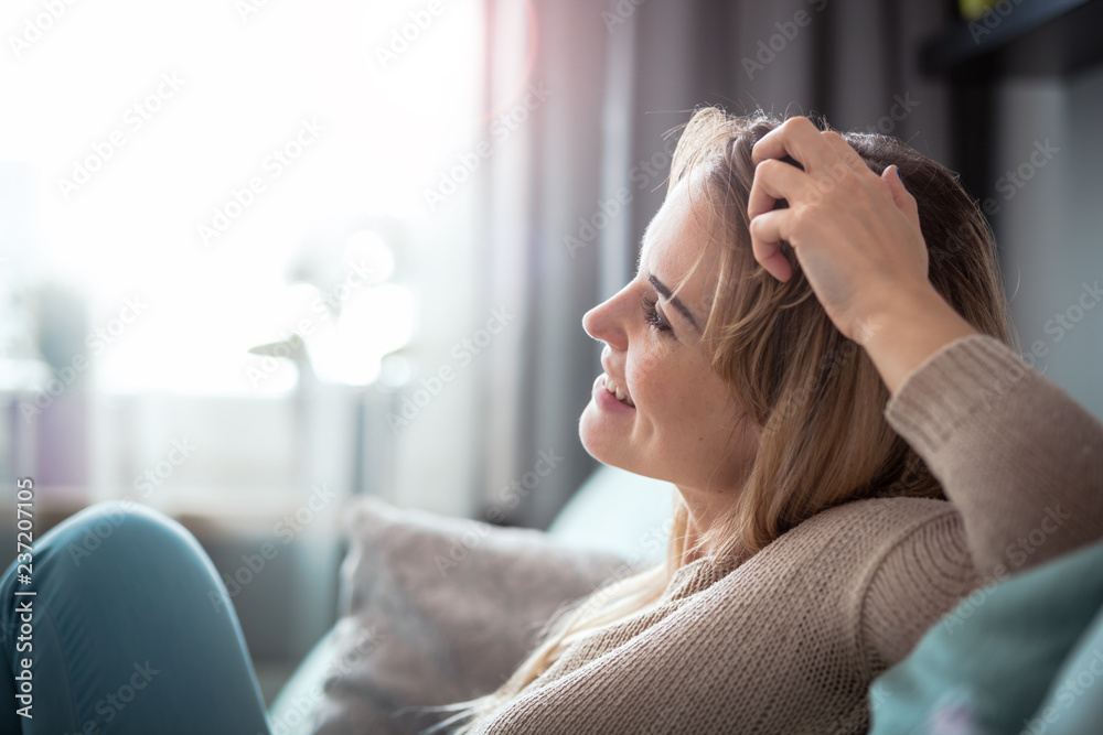 坐在家里的沙发上，笑容满面，充满积极情绪的女人