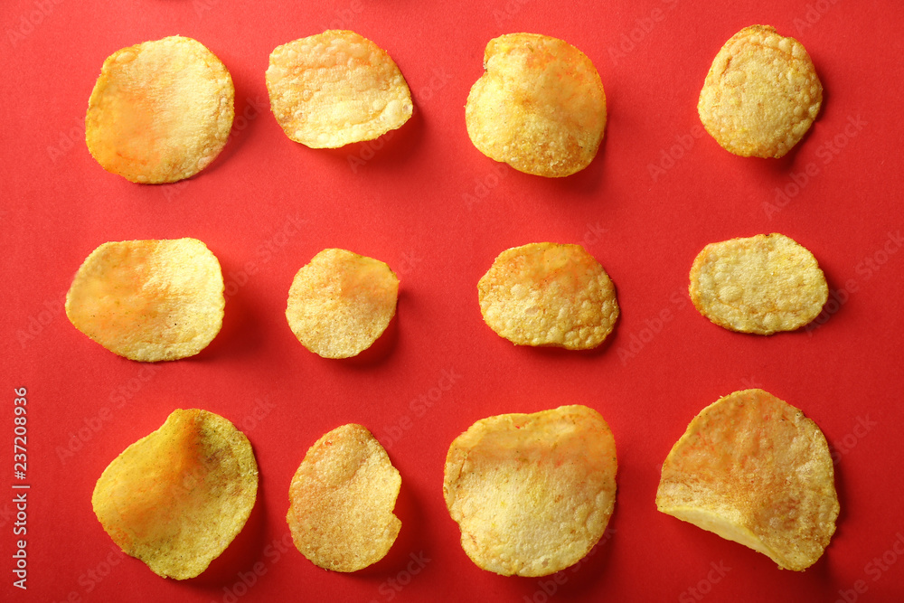 Tasty crispy potato chips on color background, top view