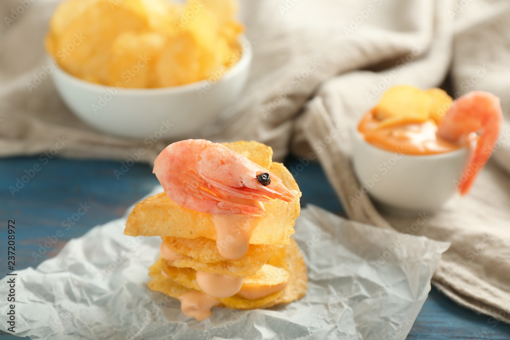 Stack of crispy potato chips with shrimps and sauce on parchment