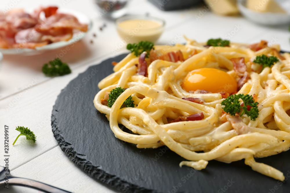 Delicious pasta carbonara on slate plate, closeup