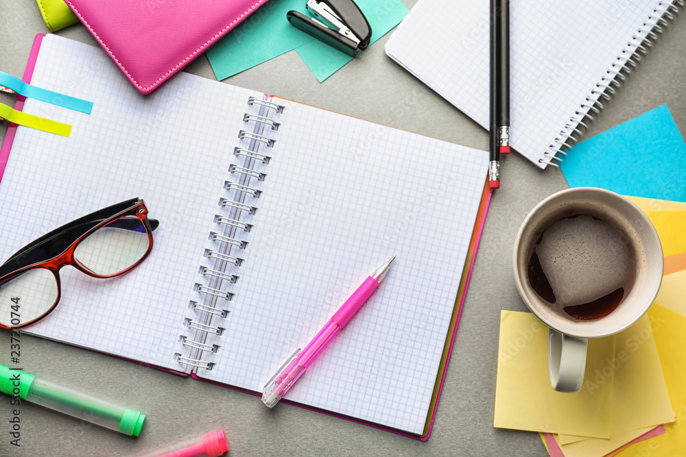 Open notebook, cup of coffee and school stationery on table, top view