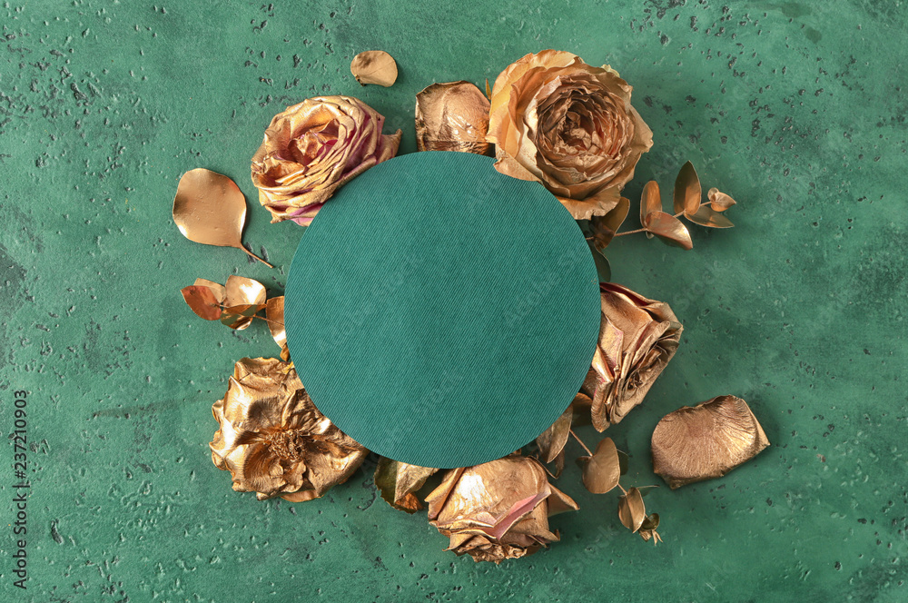 Composition with beautiful golden roses and blank card on color background