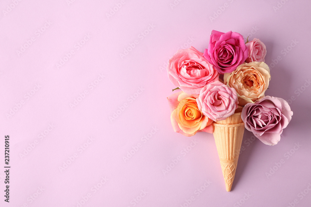 Waffle cones with beautiful roses on color background