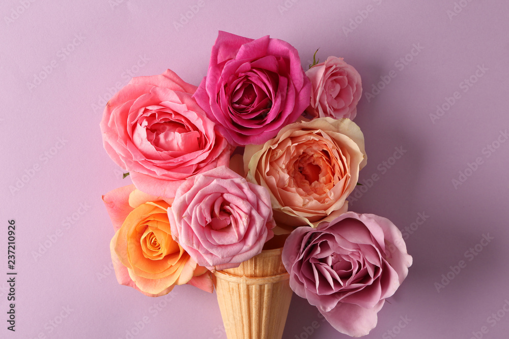 Waffle cones with beautiful roses on color background