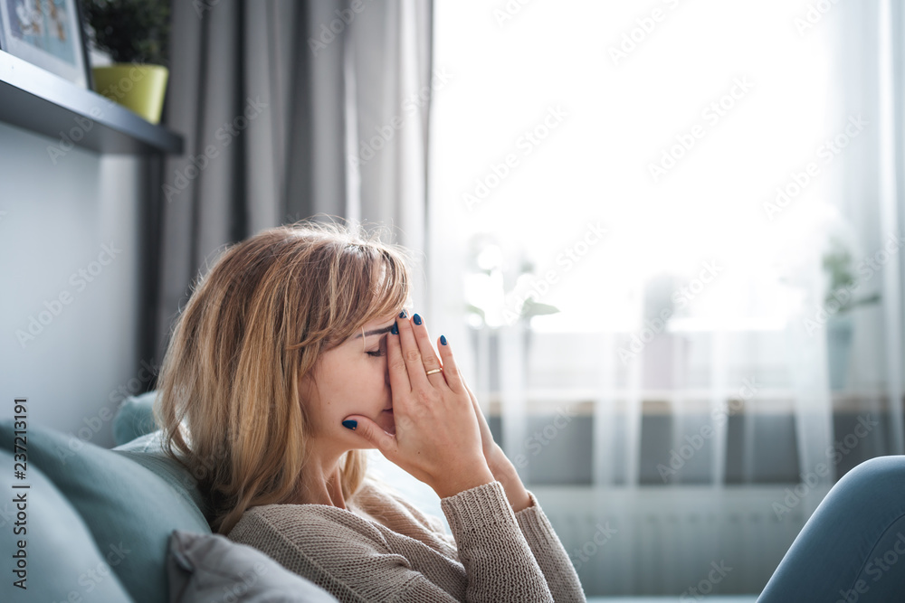 悲伤的女人坐在家里的沙发上，想着重要的事情