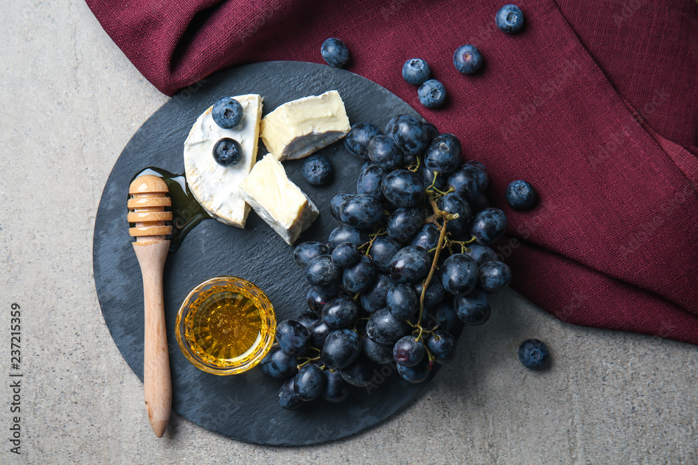 Sweet grapes with cheese and honey on grey table