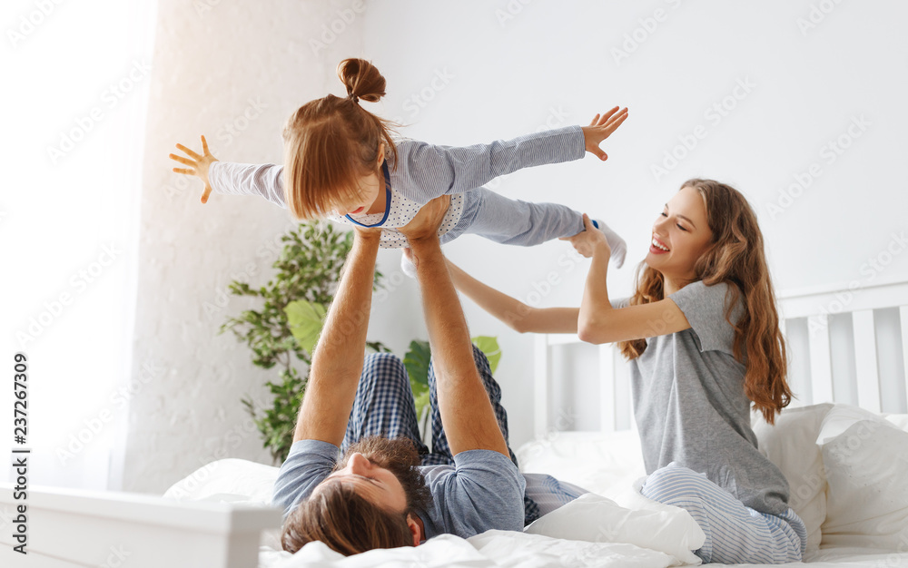 happy family mother, father and child  in bed