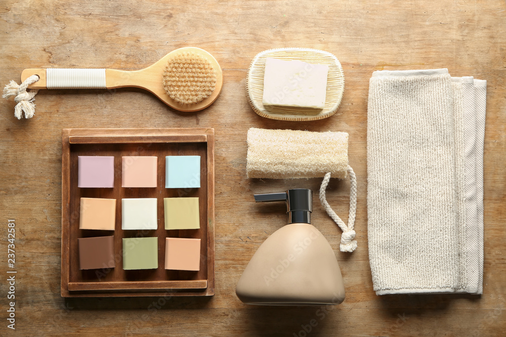 Soap bars with bath accessories on wooden background