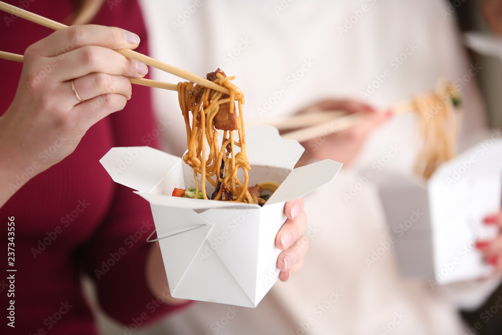 Woman eating chinese noodles from takeaway box, closeup