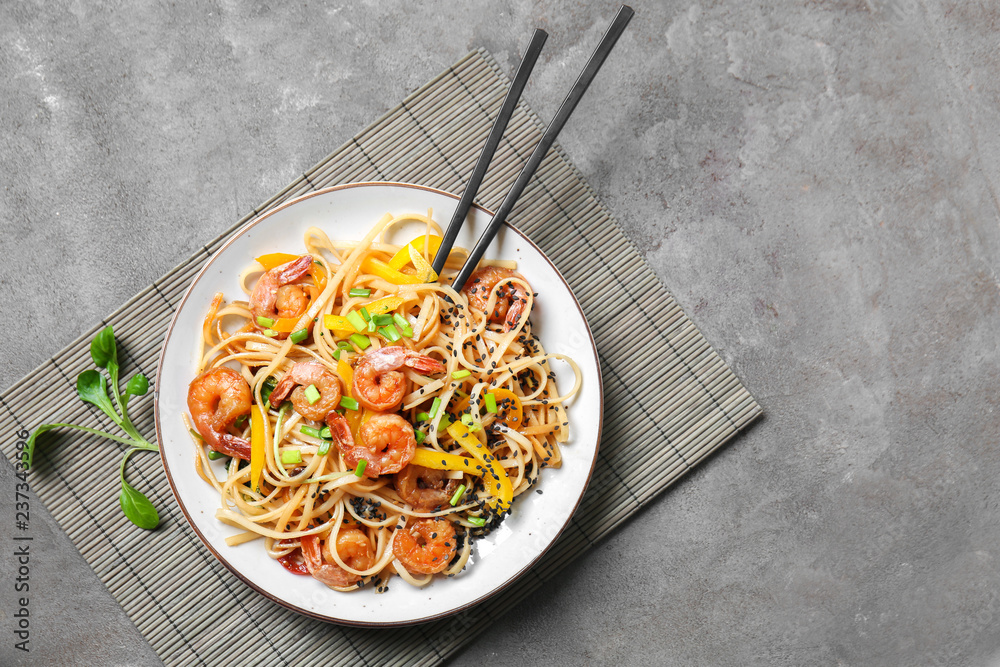 Plate with tasty chinese noodles and shrimps on table, top view