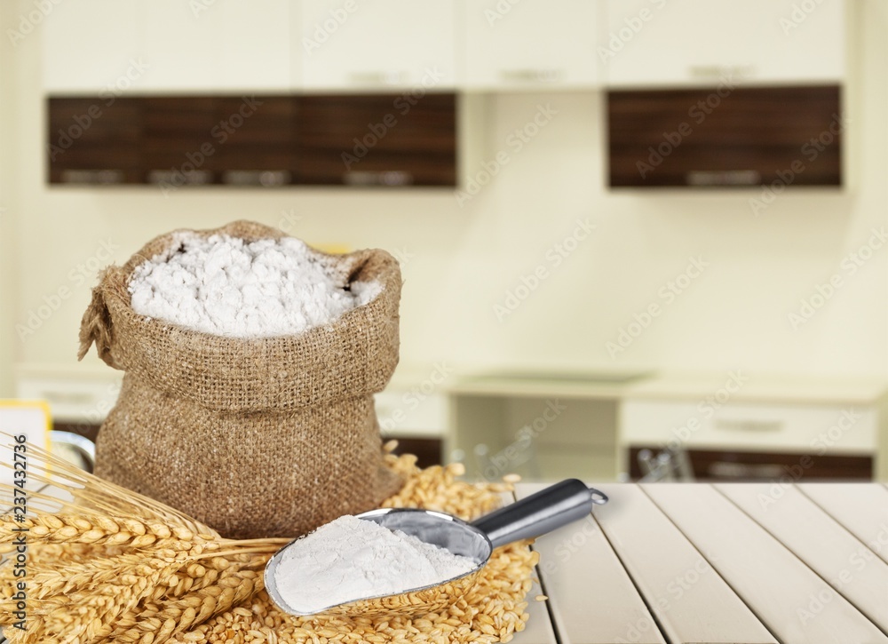 Sack of flour with wheat and scoop isolated on white background