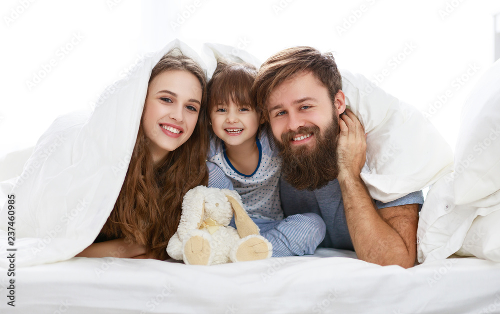 happy family mother, father and child  in bed.