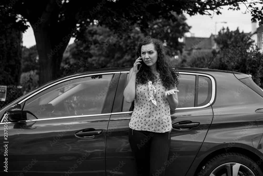 Woman standing by her car talking on the phone