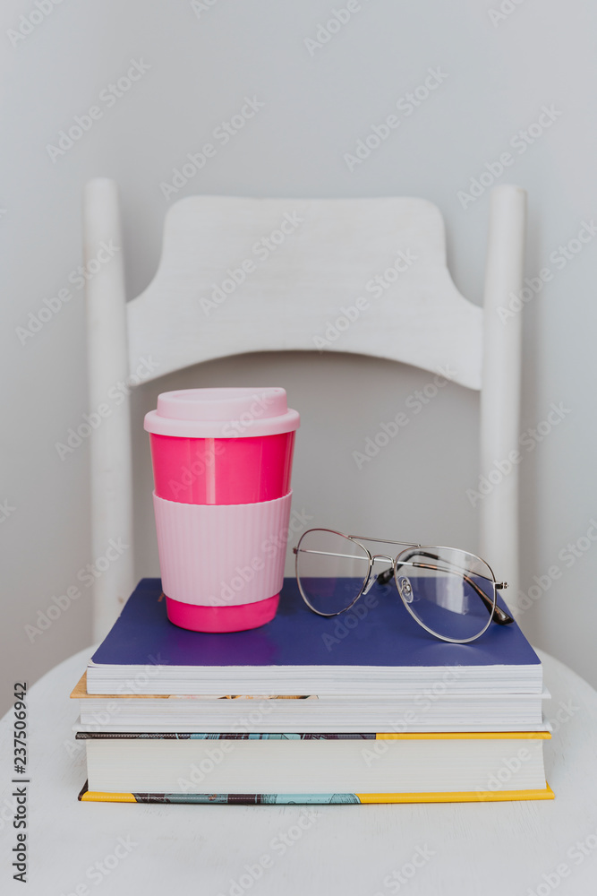 Pink travel mug on a stack of textbooks