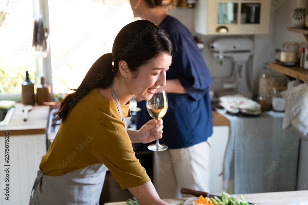 Women having white wine while cooking in a kitchen