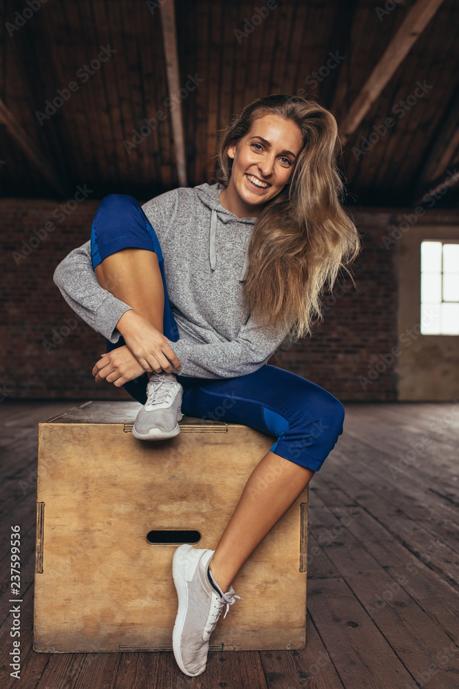 Smiling female athlete resting at cross training gym