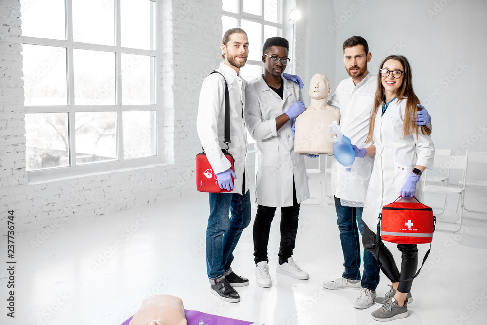 Portrait of a young team of medics in uniform standing together with medical stuff after the first a