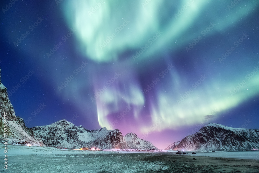 Aurora borealis on the Lofoten islands, Norway. Green northern lights above mountains. Night sky wit