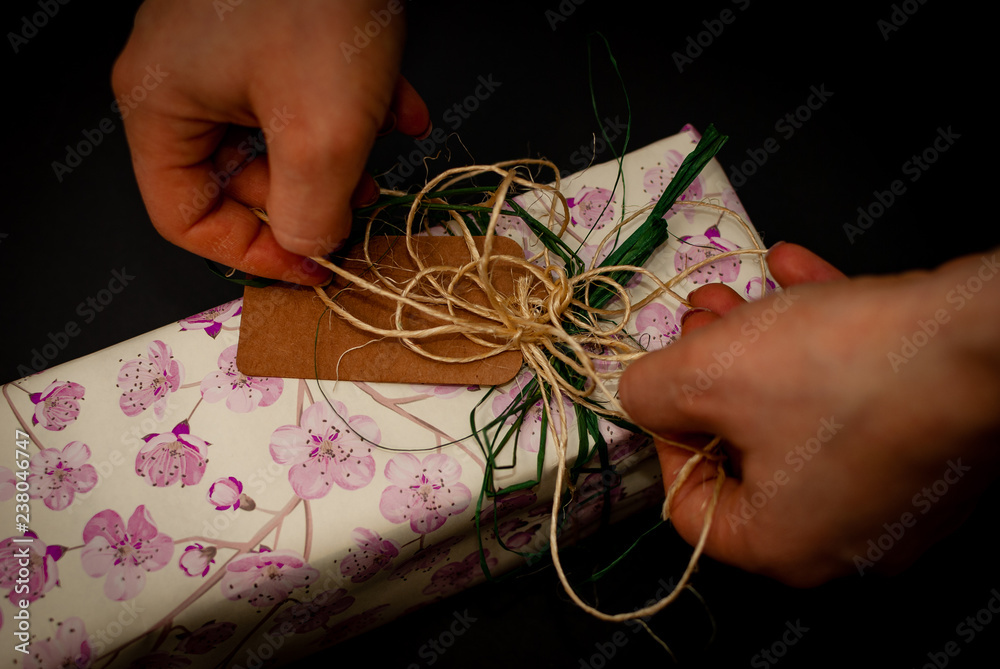 Two young female hands tying up the bow of a wrapped up present