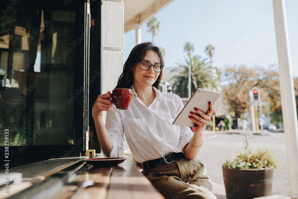 Businesswoman at cafe with cup of coffee and digital tablet