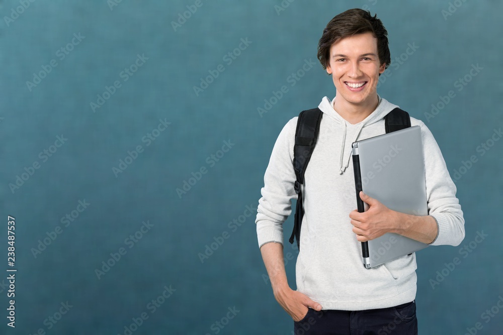 Male student with laptop smiling at camera