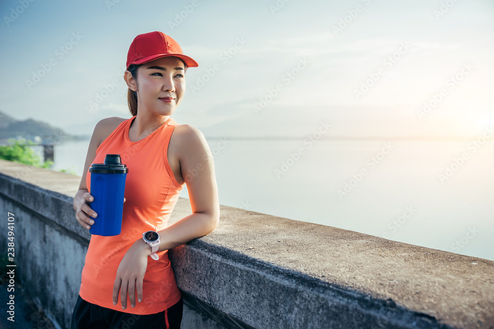 一名亚洲女运动员在水泥路上慢跑，她正在热身并整理她的tyi