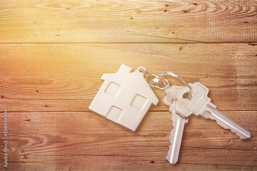 House keys with trinket on wooden background