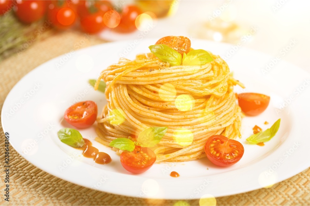 Spaghetti pasta with cherry tomatoes and basil leaves on white