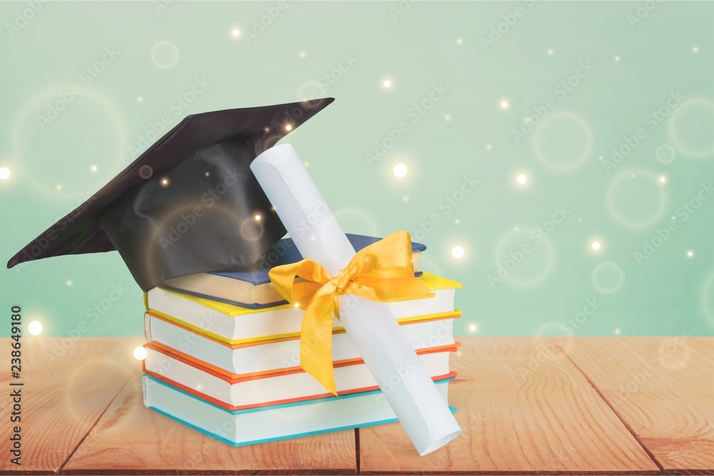 Graduation mortarboard on top of stack of books on  background