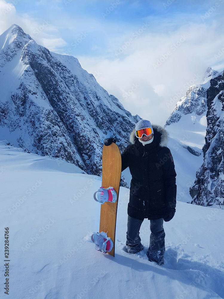 兴奋的单板滑雪运动员在下山前拿着滑雪板摆姿势。