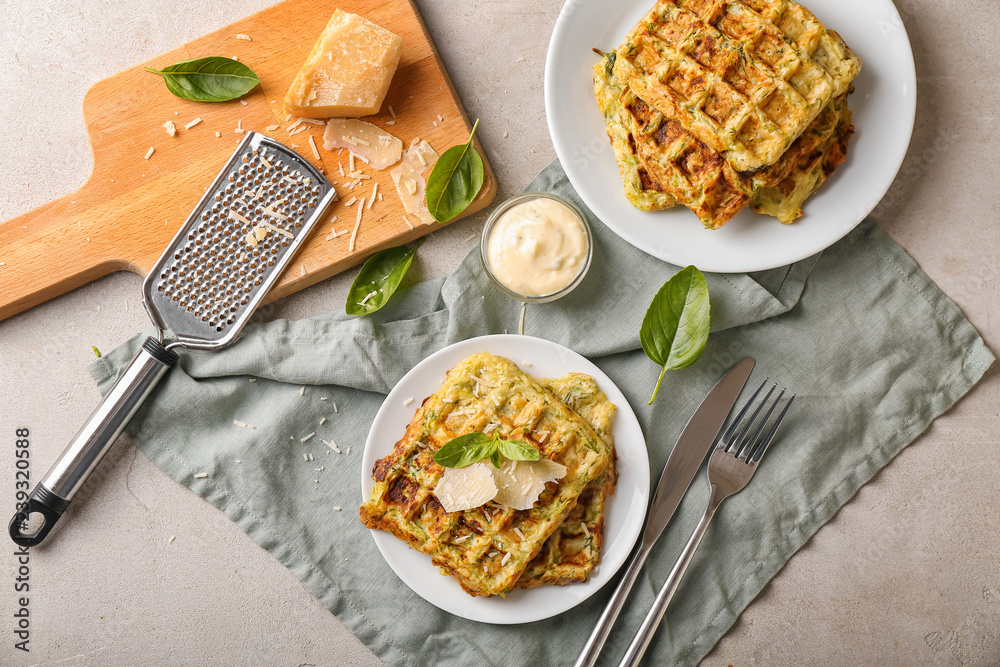 Plates with tasty squash waffles and sauce on grey table