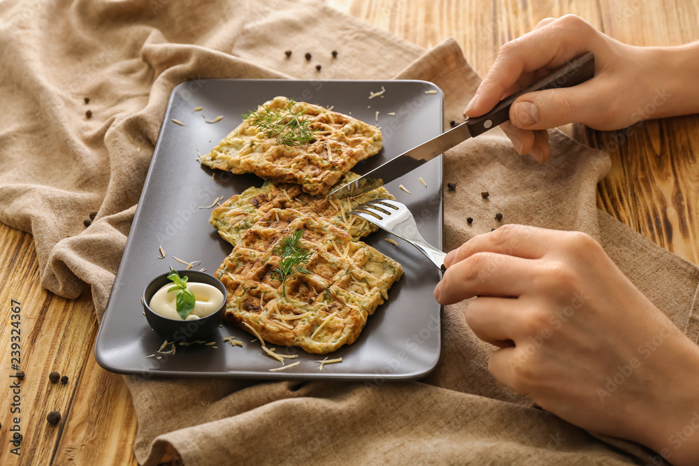 Woman eating tasty squash waffles at wooden table