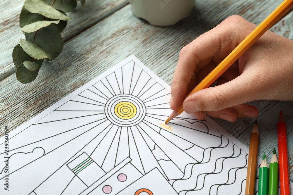 Woman coloring anti-stress picture at table