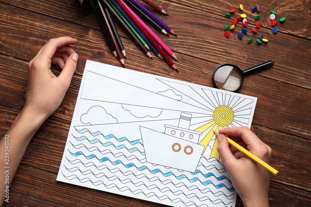 Woman coloring anti-stress picture at table