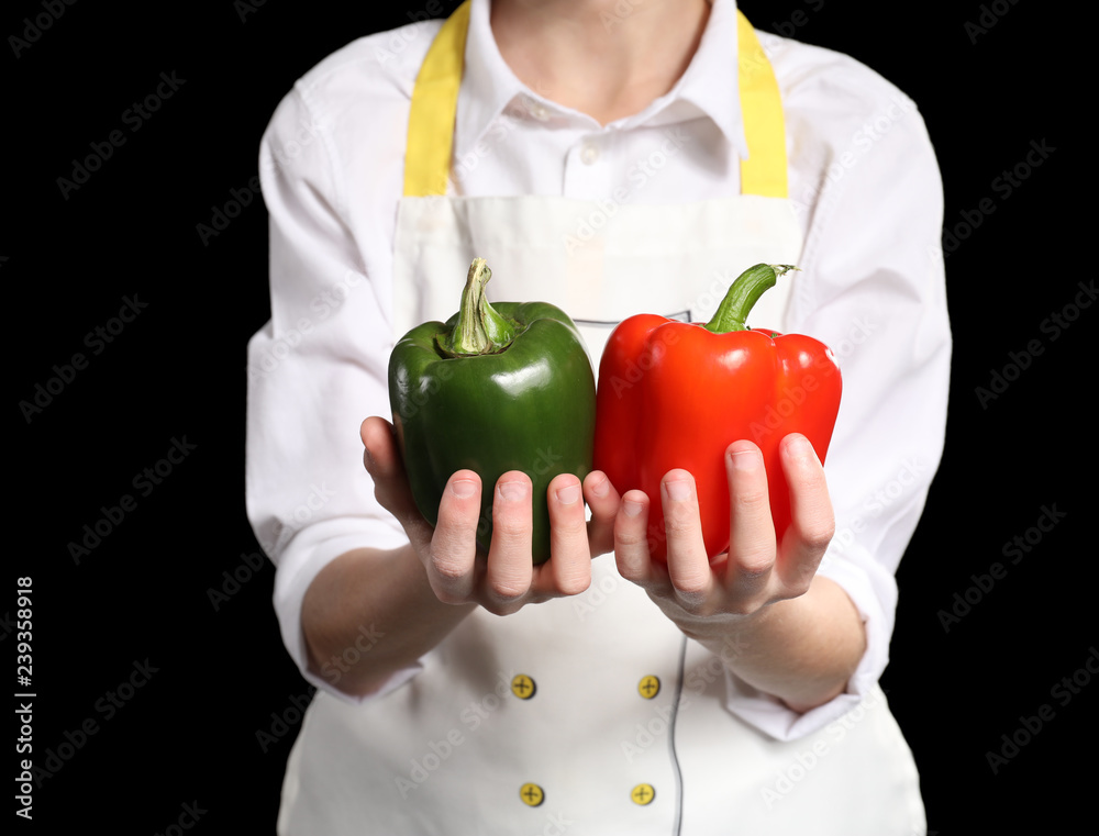 Cute little chef with peppers on dark background, closeup