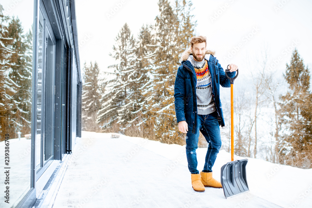 一个穿着冬装的男人拿着雪铲站在大楼露台上的肖像