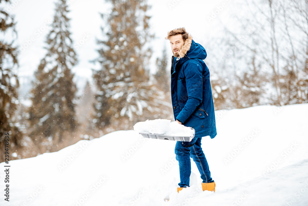 穿着冬装的男人在山上用铲子清理积雪