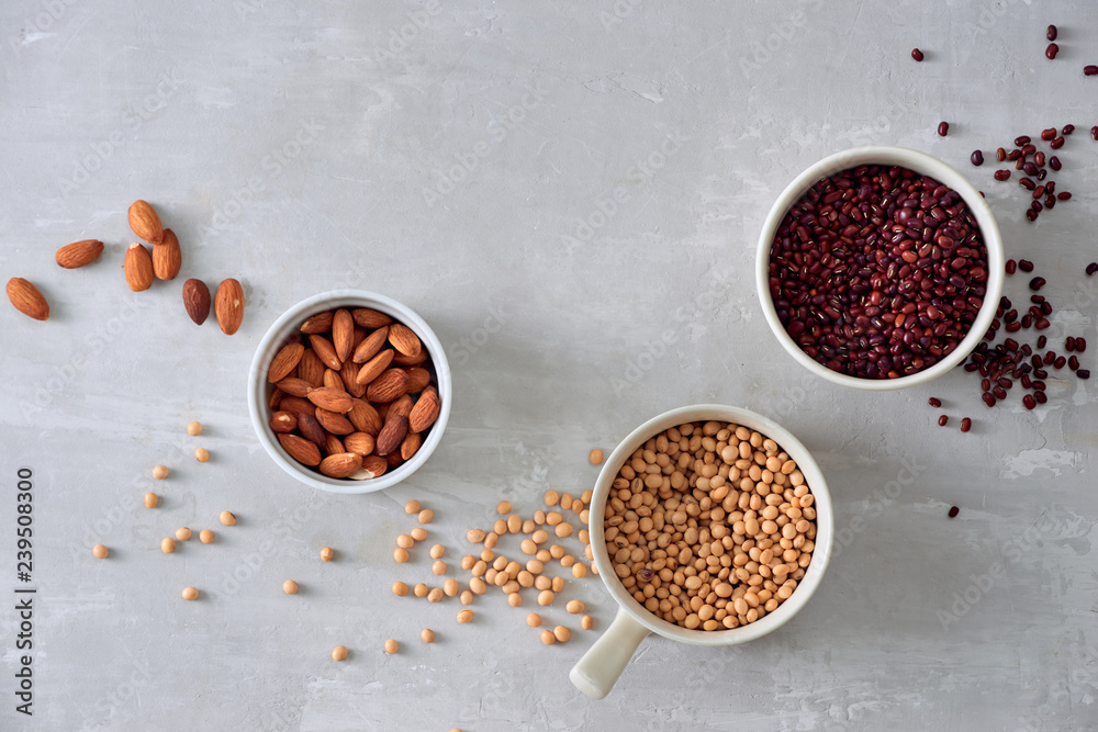 various dried beans with kitchen utensils on gray table, top view